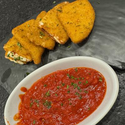 Mozzarella sticks with marinara sauce on the side.