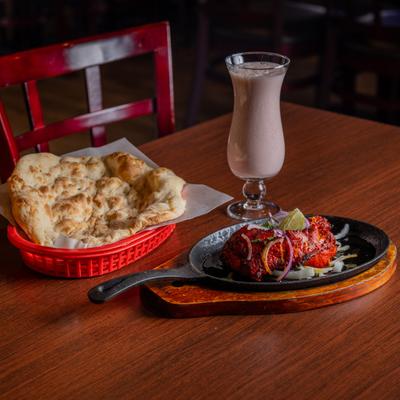 Marinated chicken leg, naan bread, and a drink.