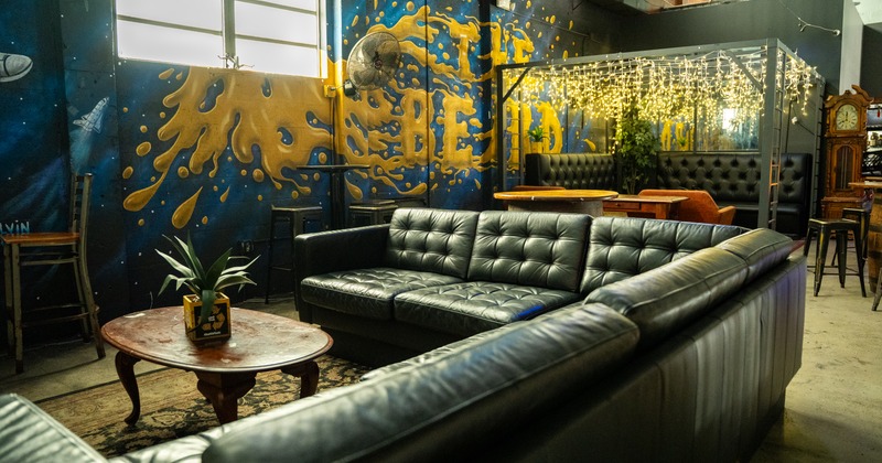 Private lounge with a couch, armchairs, decorative lighting and grafiti-style mural