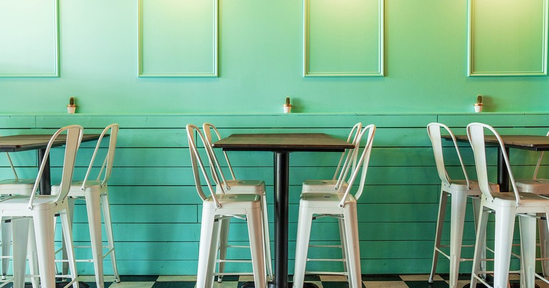 High tables and stools lined up by the green-colored wall