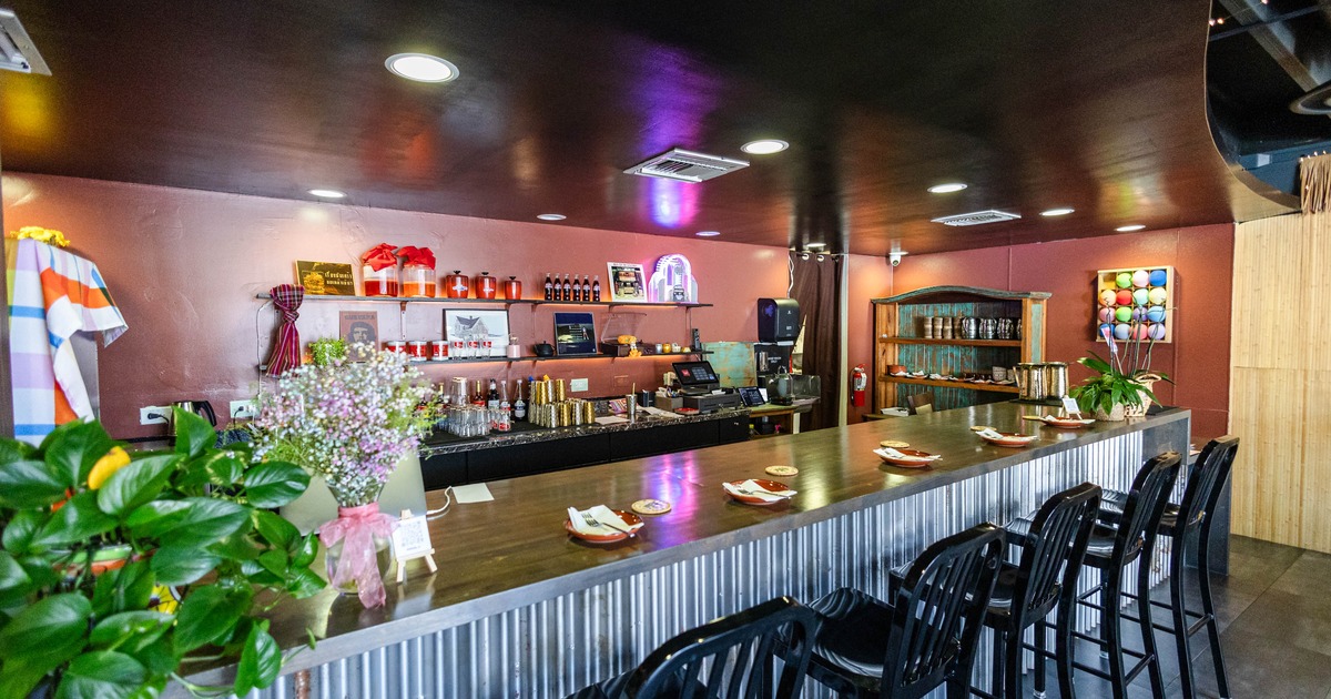 Interior of a modern café, polished wood bar, black stools, colorful beverage shelves