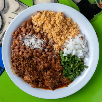 Plate of shredded beef with rice, beans, onions, and cilantro.