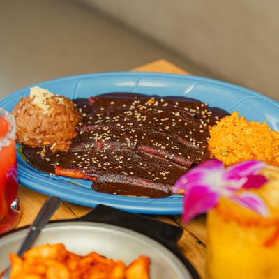 Mole enchiladas served with seasoned rice and cocktails.