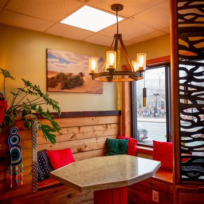 A dining table with cushions on seating, and an elegant chandelier hanging above.