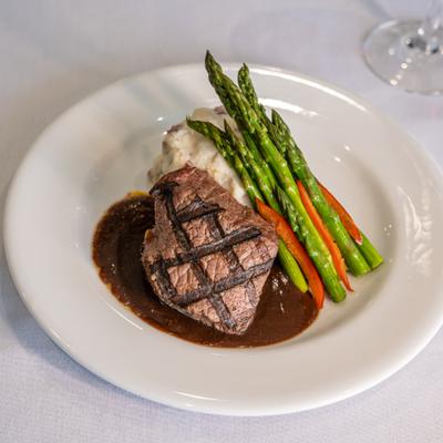 Grilled steak served with mashed potatoes, asparagus, and brown gravy.