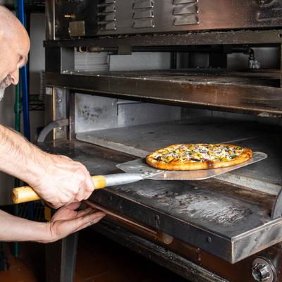 A person baking a pizza in the oven.