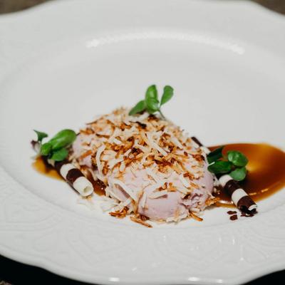 Ice cream topped with coconut flakes, drizzled with caramel sauce.