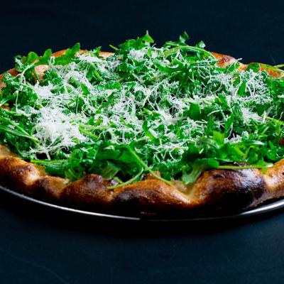 Pizza topped with arugula and grated cheese.