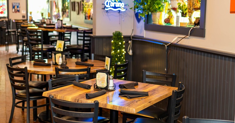 Interior of a casual dining restaurant showcasing wooden tables with black napkins