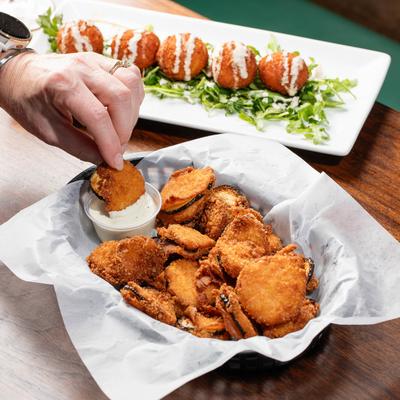 Fried Pickles, a hand dipping a fried pickle in ranch sauce.