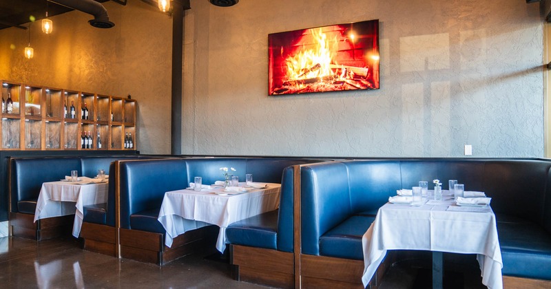 Interior, ''U'' shaped seating booths with tables, ready for guests, wine shelves on the left