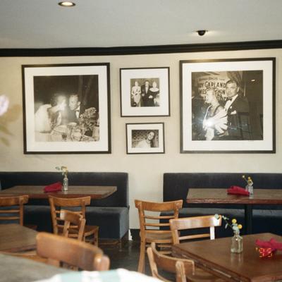 Restaurant seating area with framed vintage photographs on a wall.