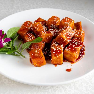 Crispy sesame tofu garnished with a mint spring and a purple orchid.