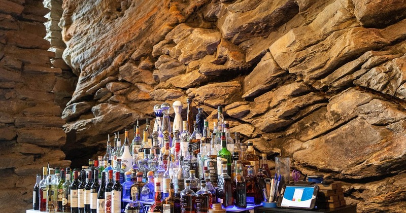Interior, a bar with wine and spirits by a rustic sedimentary rock wall