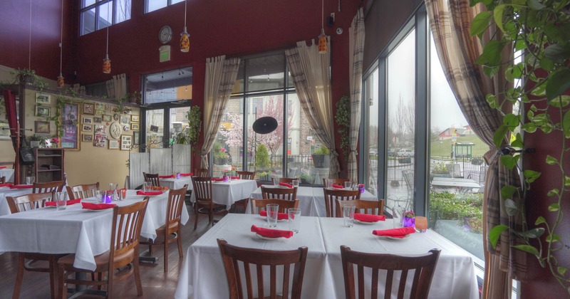 Interior, tables and chairs ready for guests, large windows, restaurant entrance in the back