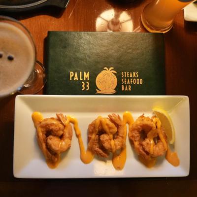 Bang bang shrimp appetizer with sauce drizzle and a lemon slice.