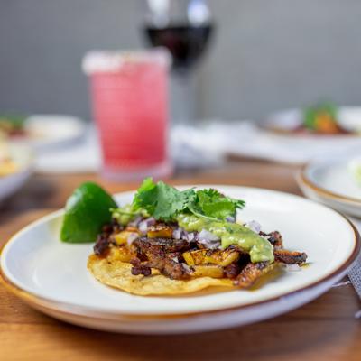 Taco with grilled meat, guacamole, onions and lime.