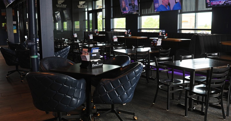 Interior of "Let It Fly" sports bar with tables, chairs and multiple televisions.
