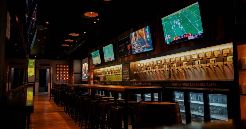 Interior of a modern bar with self-serve beer taps and multiple TVs