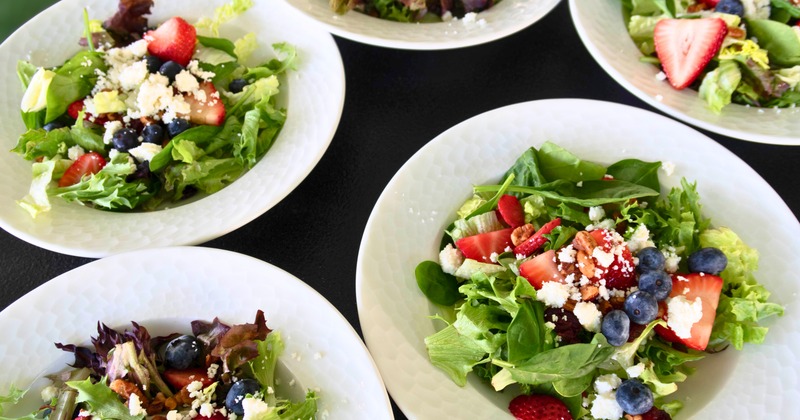 Several servings of a summer salad presented in white bowls