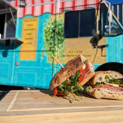 The Italian sandwich,  served outside, with a blue food truck in the background.