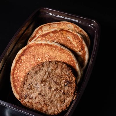 A meal of pancakes and sausage patties in a plastic meal prep container.