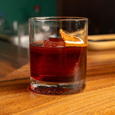 A glass of negroni on a wooden surface.