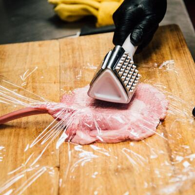 Staff member preparing meat in the kitchen