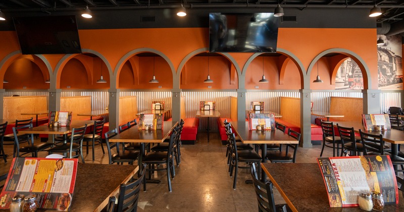 Dining room, tables and chairs in front of the booths that are under the arches