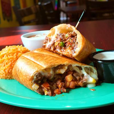 Chimichanga served alongside rice, refried beans, and sour cream.