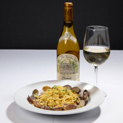 Linguine Alla Vongole served alongside bottle of white wine with a glass.