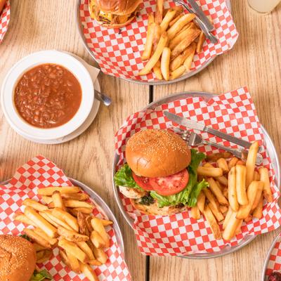 Various burgers with fries and baked beans.