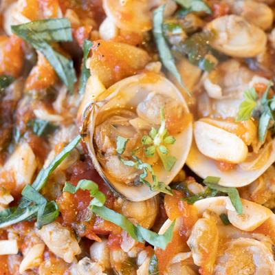 Clams in a tomato sauce with herbs, close up.