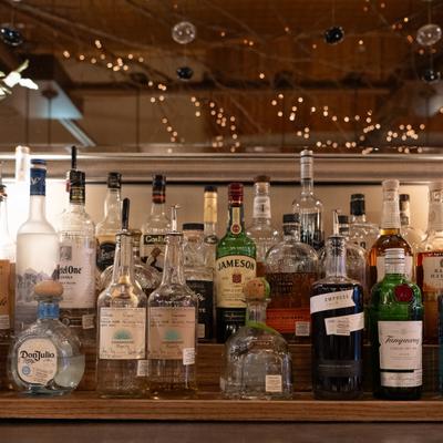 Collection of liquor bottles displayed on a wooden bar shelf.