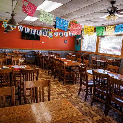 Interior with table seating set against the orange walls decorated with festive banners.