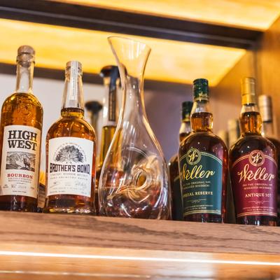 Assorted bourbon bottles on a wooden shelf.