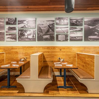 Booths and set tables beneath vintage black-and-white photographs on a wall