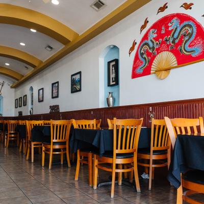 Restaurant dining area with tiled floors, framed art, and arched ceiling.