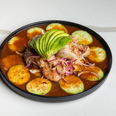 Aguachile featuring raw shrimp, sliced cucumbers, red onions, and avocado.