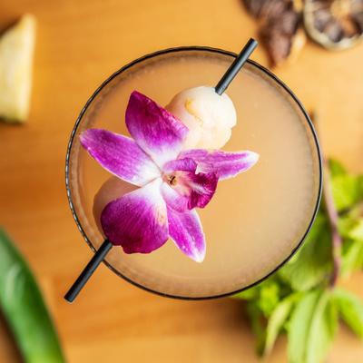 Pale cocktail garnished with a purple orchid.