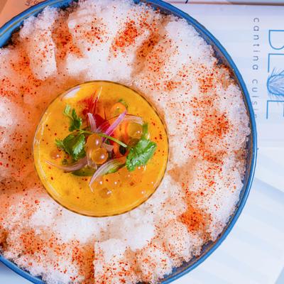 Mango seafood ceviche in a glass over crushed ice with chili.