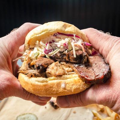 Hands holding a Smoko Loco sandwich, close-up.