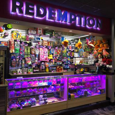 Arcade redemption prize counter with glass displays filled with vibrant toys.