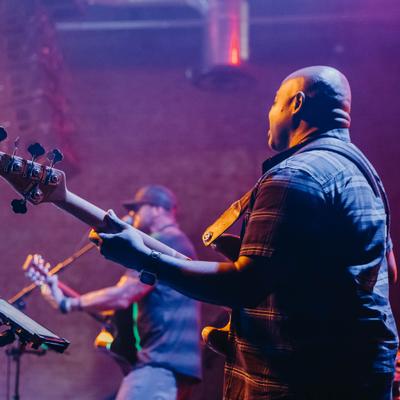 Live band performing on stage under purple and blue stage lights.