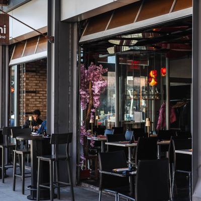 Storefront and outdoor dining area with high-top tables and chairs.