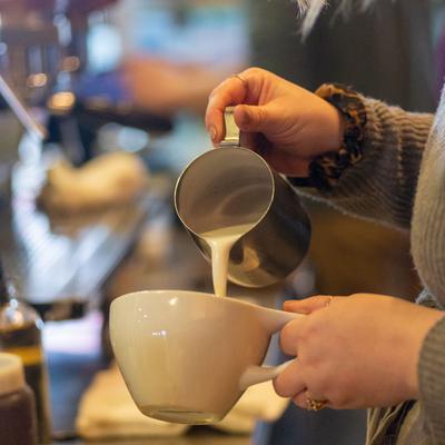 Interior, barista pouring milk into a cup