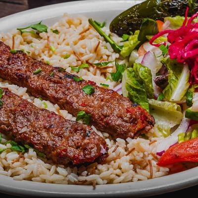 Lamb Shish Kebab served over rice with a salad on the side.