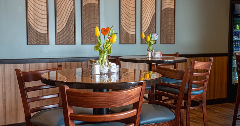 Interior, closeup on a round tables for three, vase with tulips as a centerpiece