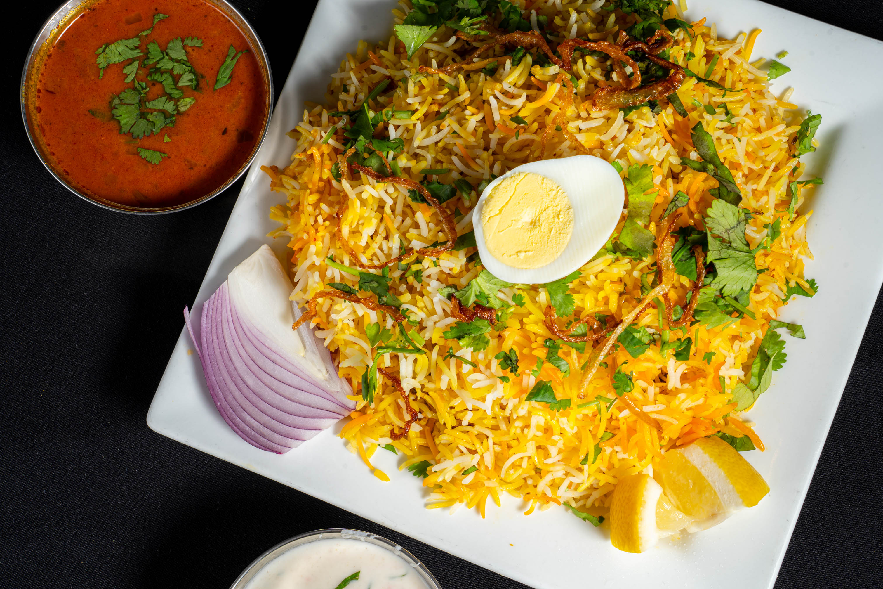 A plate of biryani with a slice of boiled egg