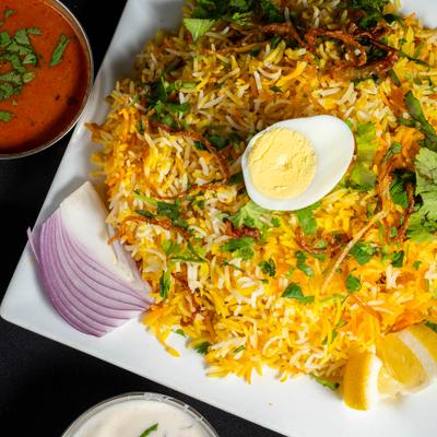 A plate of biryani with a slice of boiled egg.